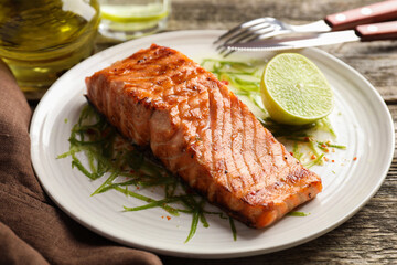 Delicious grilled salmon fillet served on wooden table, closeup