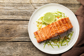Delicious grilled salmon fillet served on wooden table, top view. Space for text