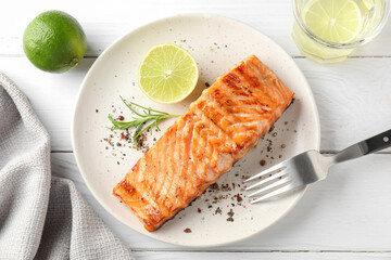 Delicious grilled salmon fillet served on white wooden table, flat lay