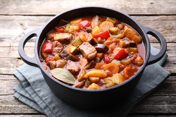 Delicious stew with vegetables in pot on wooden table, closeup