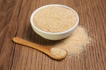 Oat bran in bowl and spoon on wooden table, closeup