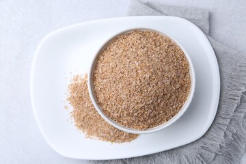 Buckwheat bran in bowl on light grey table, top view