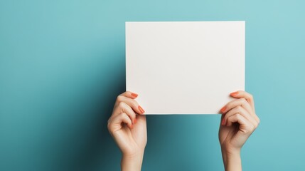Person holding a blank white sheet of paper against a blue background, showcasing design projects or presentations