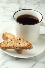 Traditional Italian almond biscuits (Cantucci) and mug of coffee on white marble table, closeup