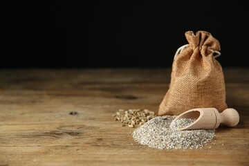 Pile of fresh rye bran, scoop and sack on wooden table. Space for text