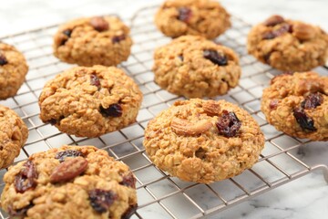 Delicious oatmeal cookies with raisins and nuts on white marble table, closeup