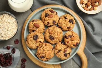 Delicious oatmeal cookies with raisins and nuts on grey table, flat lay