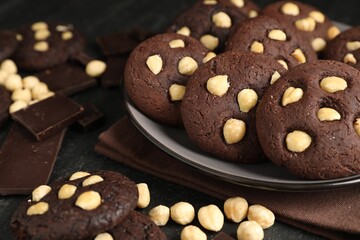 Tasty chocolate cookies with hazelnuts on black table, closeup