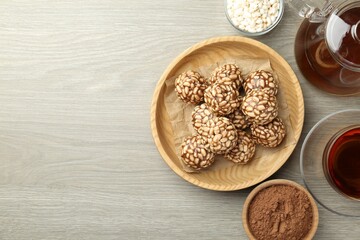 Tasty chocolate puffed rice balls served with tea on wooden table, flat lay. Space for text