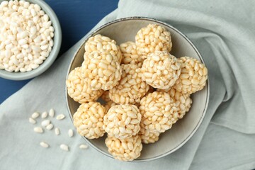 Tasty puffed rice balls and grains on blue table, top view