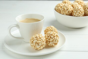 Tasty puffed rice balls and coffee on white wooden table, closeup