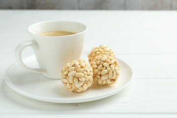 Tasty puffed rice balls and coffee on white wooden table, closeup