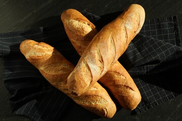 Freshly baked baguettes on black table, top view