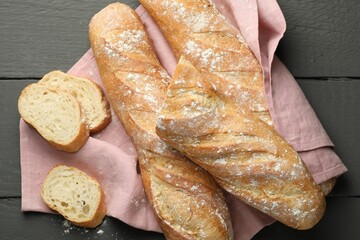 Cut fresh baguettes on grey wooden table, top view