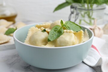 Delicious ravioli with cheese and basil served on white marble table, closeup