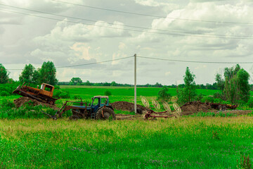 A tractor plows a field with a plow for spring sowing of seeds. An agricultural machine works in the countryside. Sowing wheat. Close-up.Postcard.