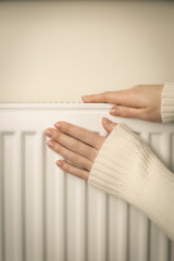 Individual home heating system. Female hands on a warm radiator.