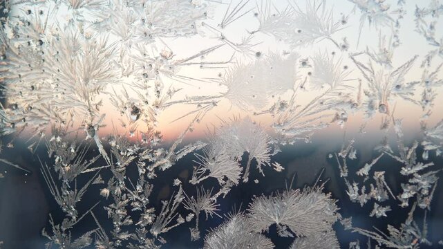 Left pan shot background with frost pattern on glass early winter morning. Real beautiful pattern on window made of ice floes at low negative air temperature.