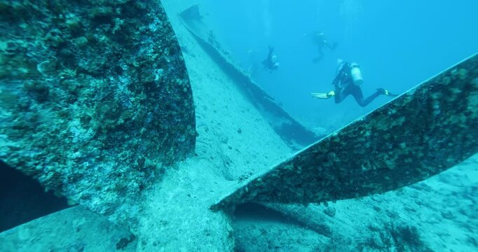 Divers explore the wreck of the SS Thistlegorm. Top diving wreck dives. Swimming over the propeller and cargo in hold of Thistlegorm shipwreck in the Red Sea, Sharm el Sheikh, Egypt.