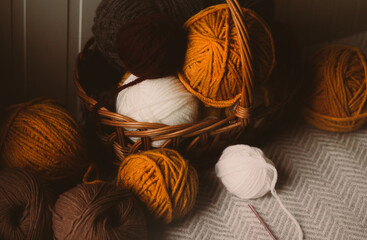Colorful balls of yarn can be found in a wooden basket at home. They are used for crochet, a...