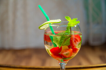 Non-alcoholic cocktail strawberry kiwi lime and mint in a glass on a wooden table