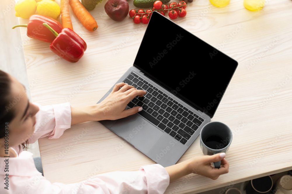 Aufkleber Breakfast Concept. Above top high angle view of young female using personal computer with black empty screen for mock up design, checking email or browsing internet sitting at table drinking coffee