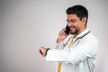 smiling doctor looks at the watch on his wrist, exuding confidence and professionalism. He checks the time during a busy day at the clinic, showcasing a calm and positive demeanor in a medical setti