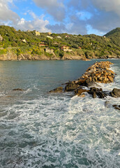 Waves break on breakwater of Mediterranean Sea. Nature of sea and mountains of Italy. Sunset in Setri Levante, Liguria.