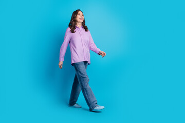 Full length photo of cheerful pretty lady dressed puple blouse walking empty space isolated blue...