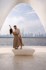 Young couple in love visiting Dubai with the backdrop of the city skyline as they enjoy holding each other close.