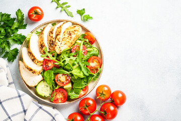 Green salad with chicken steak and fresh vegetables at black table. Top view with copy space.