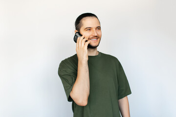 Portrait of young smiling man talking on smartphone, on white background.