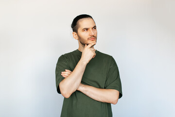 Portrait of young thoughtful man, touching his chin while looking away, on white background.