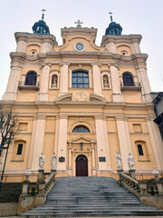 Fototapeta premium View of the facade of a picturesque yellow Catholic church and the stairs to it. Historical and religious heritage. Bottom view