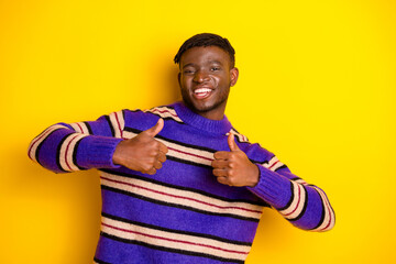 Photo of nice young man demonstrate thumb up wear pullover isolated on yellow color background