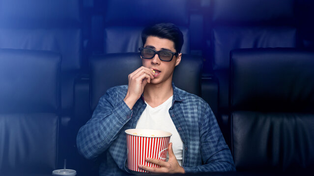 Handsome young man in 3D glasses watching interesting movie in cinema