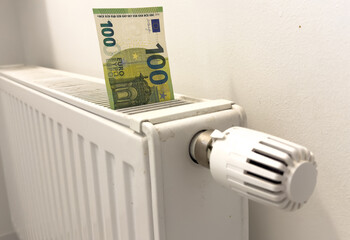 A heating radiator battery from which bills stick out. The concept of high heating expenses. Rise in energy prices, energy crisis and recession