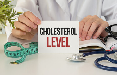 Doctor Holding Cholesterol Level Card at Desk with Stethoscope and Measuring Tape
