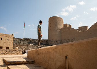 A man explores the ancient Bahla Fort, a UNESCO World Heritage Site in Oman, discovering its historical architecture and panoramic views.