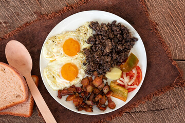 Traditional Brazilian everyday food, black bean stew, bacon, egg, salad, pickles. Real rustic food