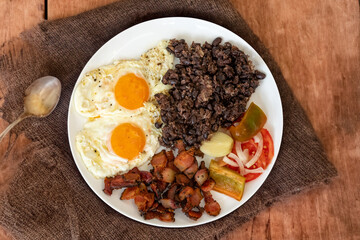 Traditional Brazilian everyday food, black bean stew, bacon, egg, salad, pickles. Real rustic food
