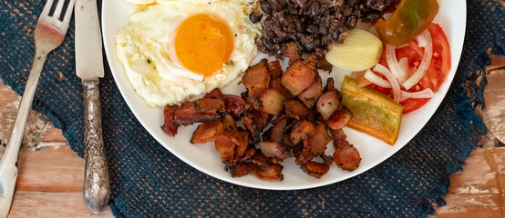 Traditional Brazilian everyday food, black bean stew, bacon, egg, salad, pickles. Real rustic food