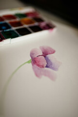 painted watercolor flower on a paper with palette on the background