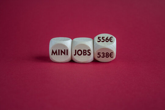 Cubes with symbol for the raise of the income limit for tax free 'mini jobs' in Germany from 538 Euro to 556 Euro in 2025. Beautiful red background. Business concept.