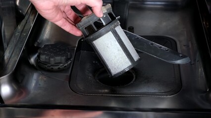 A hand taking out dishwasher filter to clean it, dis washer cleaning concept, kitchen home...