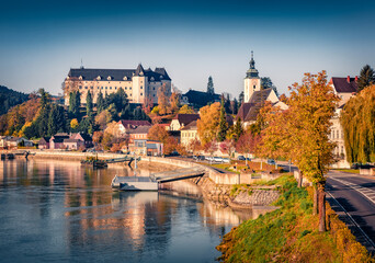 Obraz premium Sunny autumn view of Greinburg Castle on the shore of Danube river. Colorful morning cityscape of Greinburg town, district Perg, Austria, Europe. Traveling concept background.