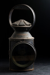 Dark and moody image of a rusted Vintage railway signal hand lantern or lamp on a black background © Bassey