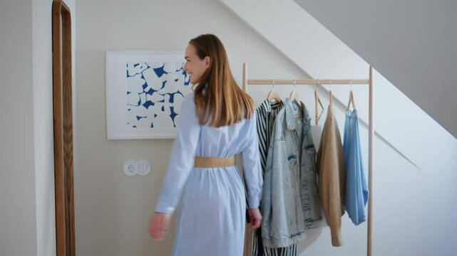 Happy girl choosing dress looking reflection at home. Lady thinking what to wear