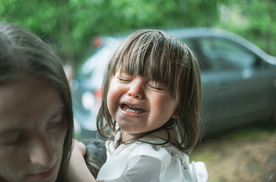 A cute little girl is having a tantrum and is crying while her mother tries to comfort her by holding her