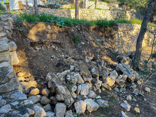 Collapsed stone retaining wall with scattered rubble